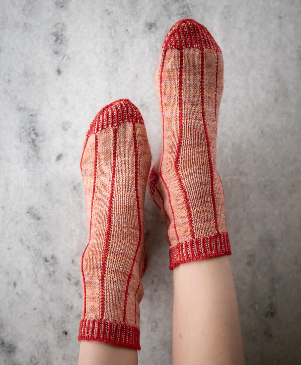 April Socks Knitting Pattern Main Image being worn on feet in front of a marble background