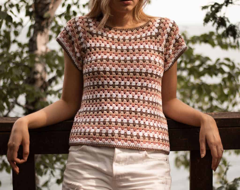 detail image of maria top showing the individual granny stitches and stripe detailing. Image is closeup with light shining on the top and shaded trees behind