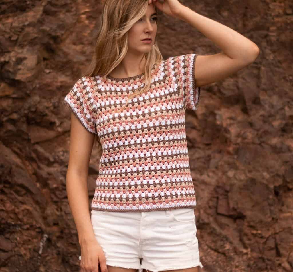 main image of maria crochet top being worn by model with her arm up through her hair showing the raglan detailing and the relaxed fit of sleeves