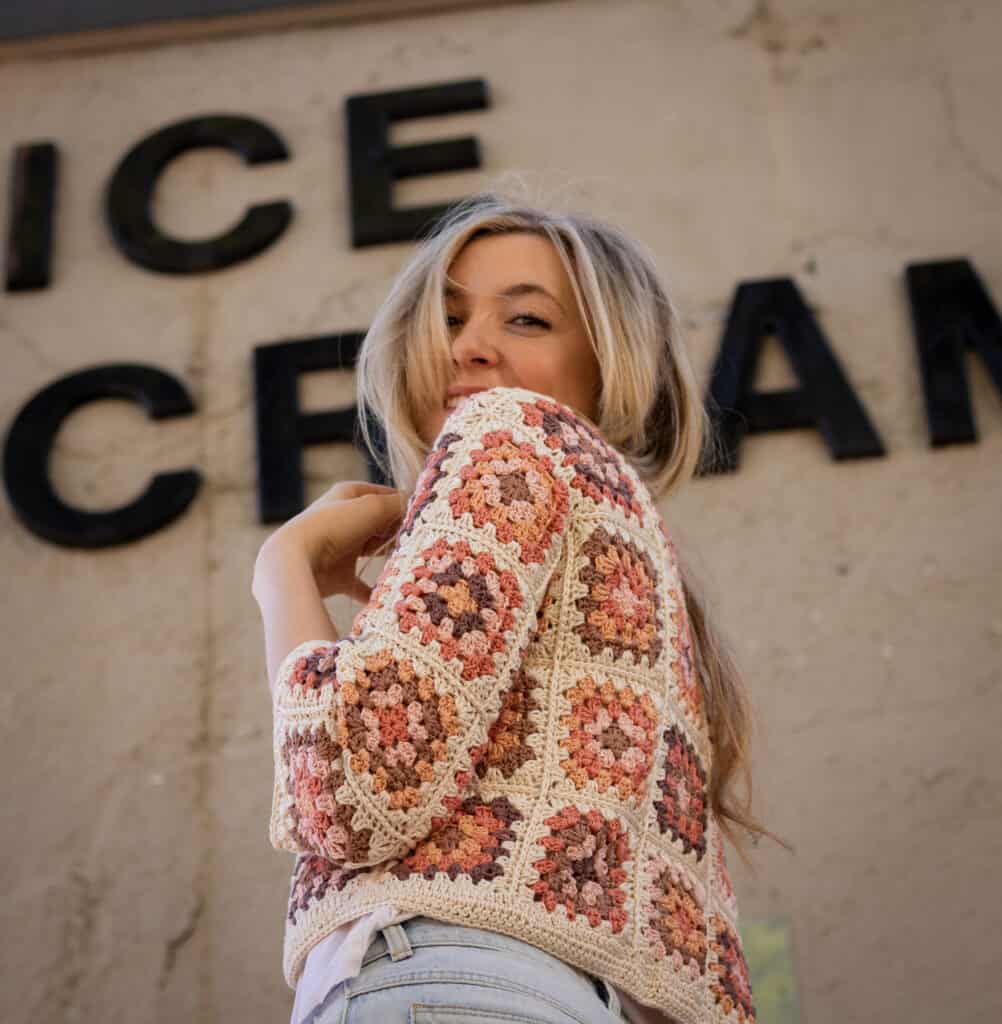 model wearing a vintage inspired crochet cardigan smiling in front of an ice cream sign
