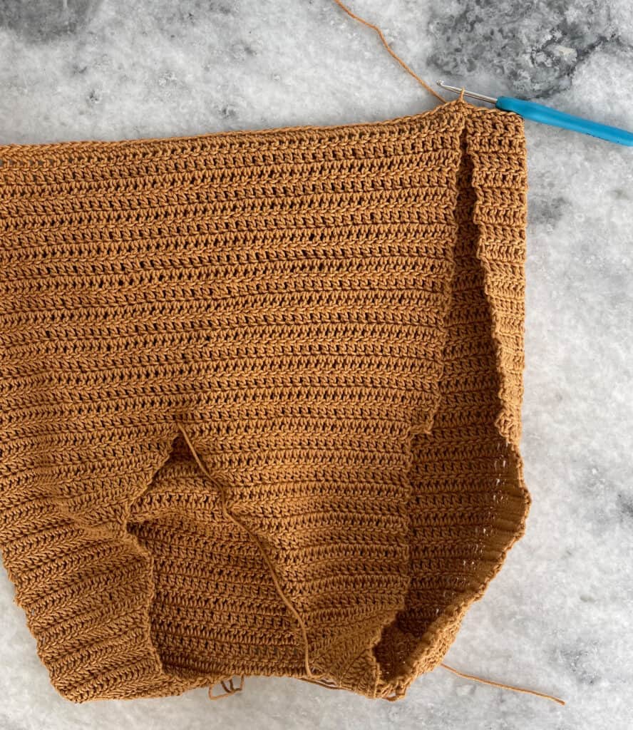In this photo, you can see how the bodice pieces will be joined together with a slipped stitch. The opening left on either side of the bodice will be seamed after working the skirt.