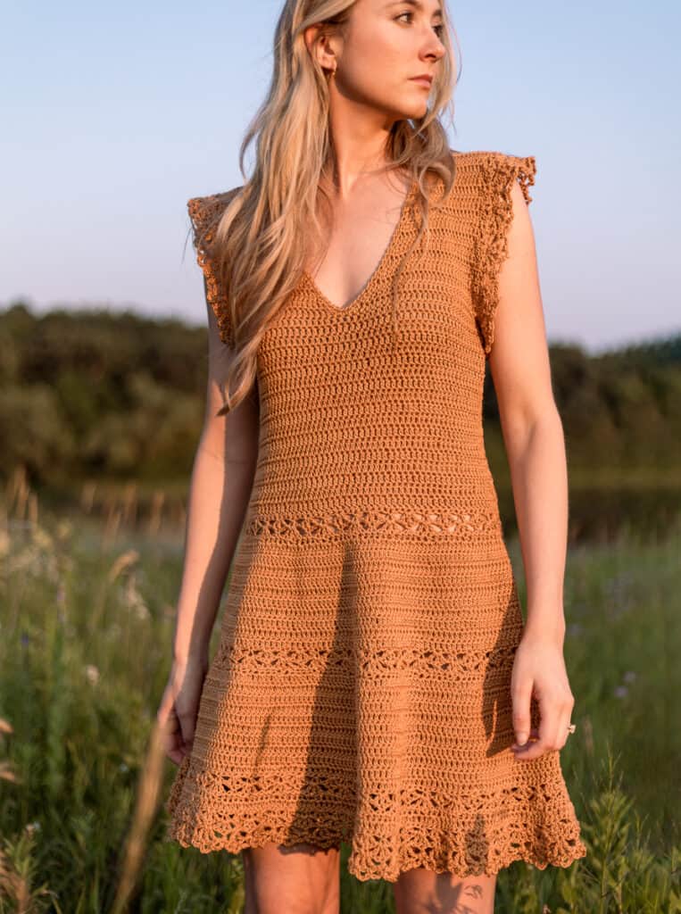 Closeup image showing details of sundress. Textured and lace crochet stitches make a unique tiered design on the skirt