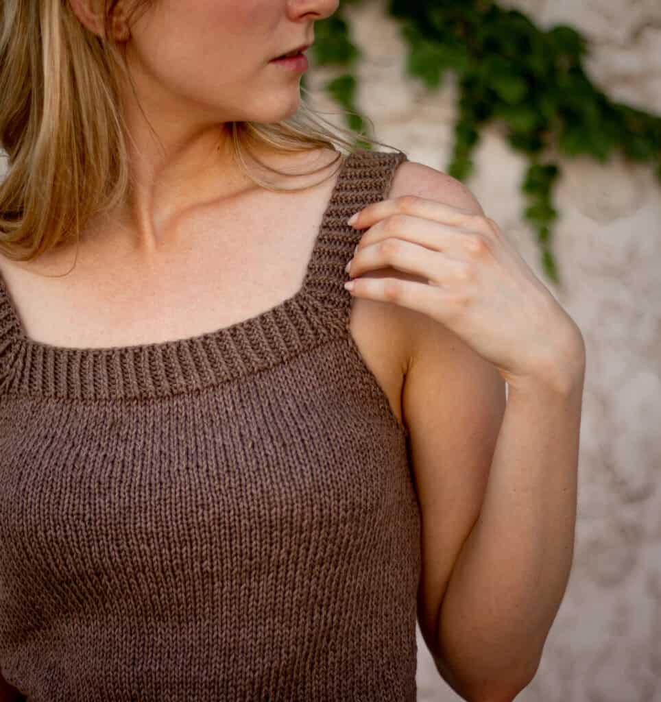 closeup image of the tank top knitting pattern showing stitches and twisted rib accent on the neckline