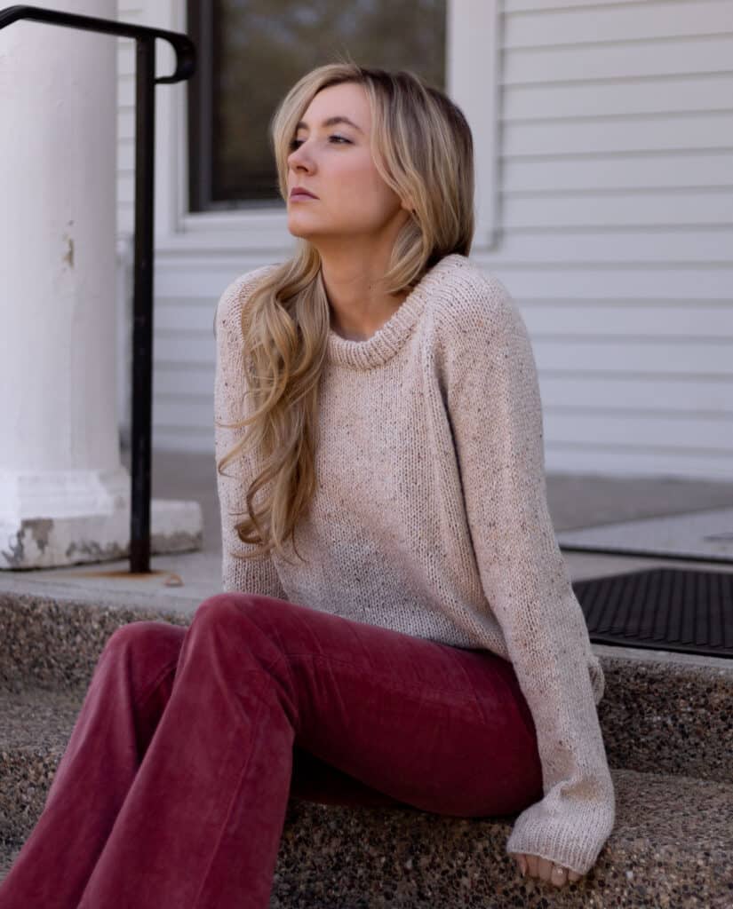 Woman wearing a tweed sweater looking away from the camera. Raglan style sweater looks cozy with a relaxed fit.