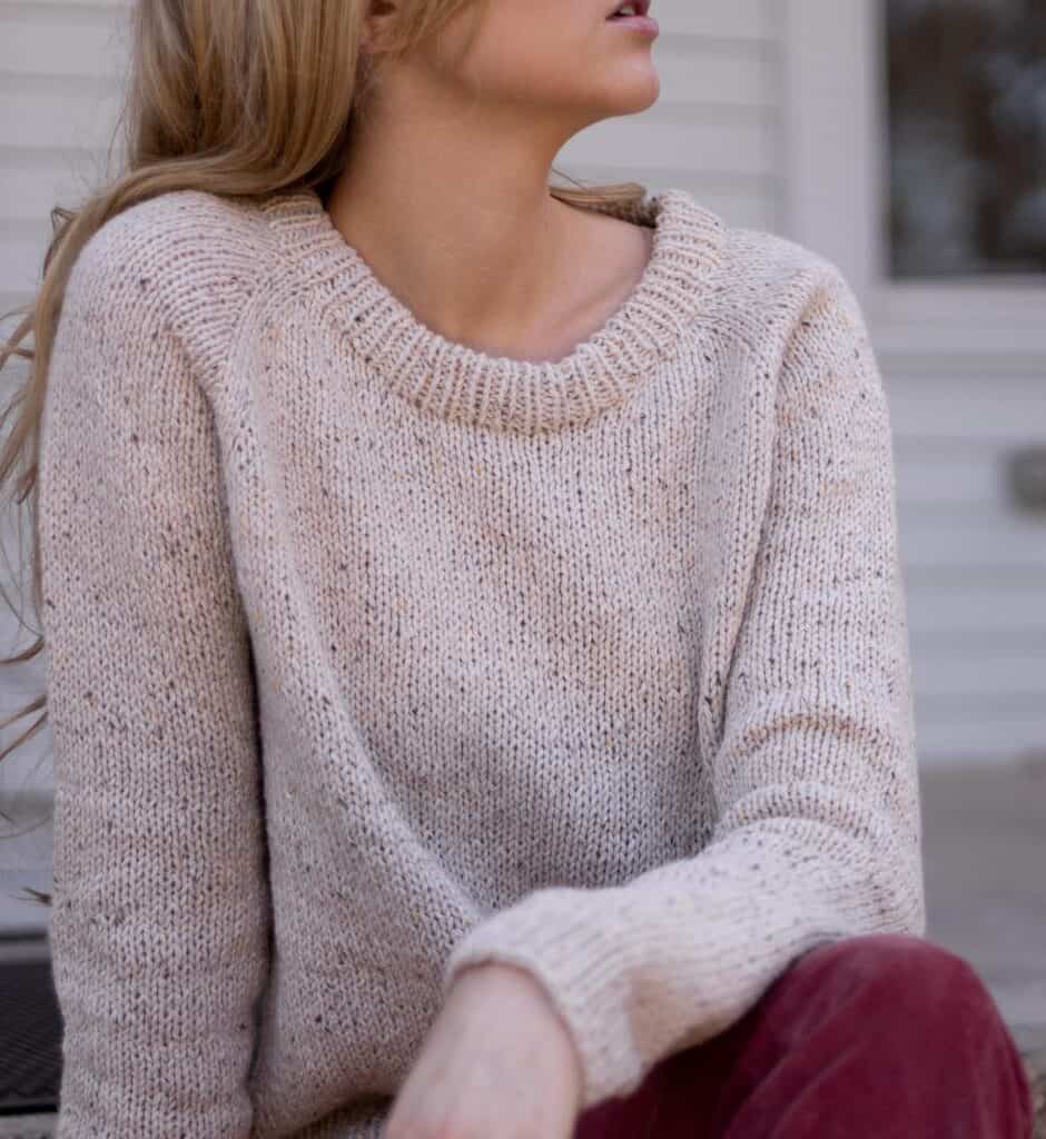 close up neckline detailing of the October Sweater knitting pattern being worn on a model. The neckline is nicely shaped and finished. Photo displays the top down raglan style increases